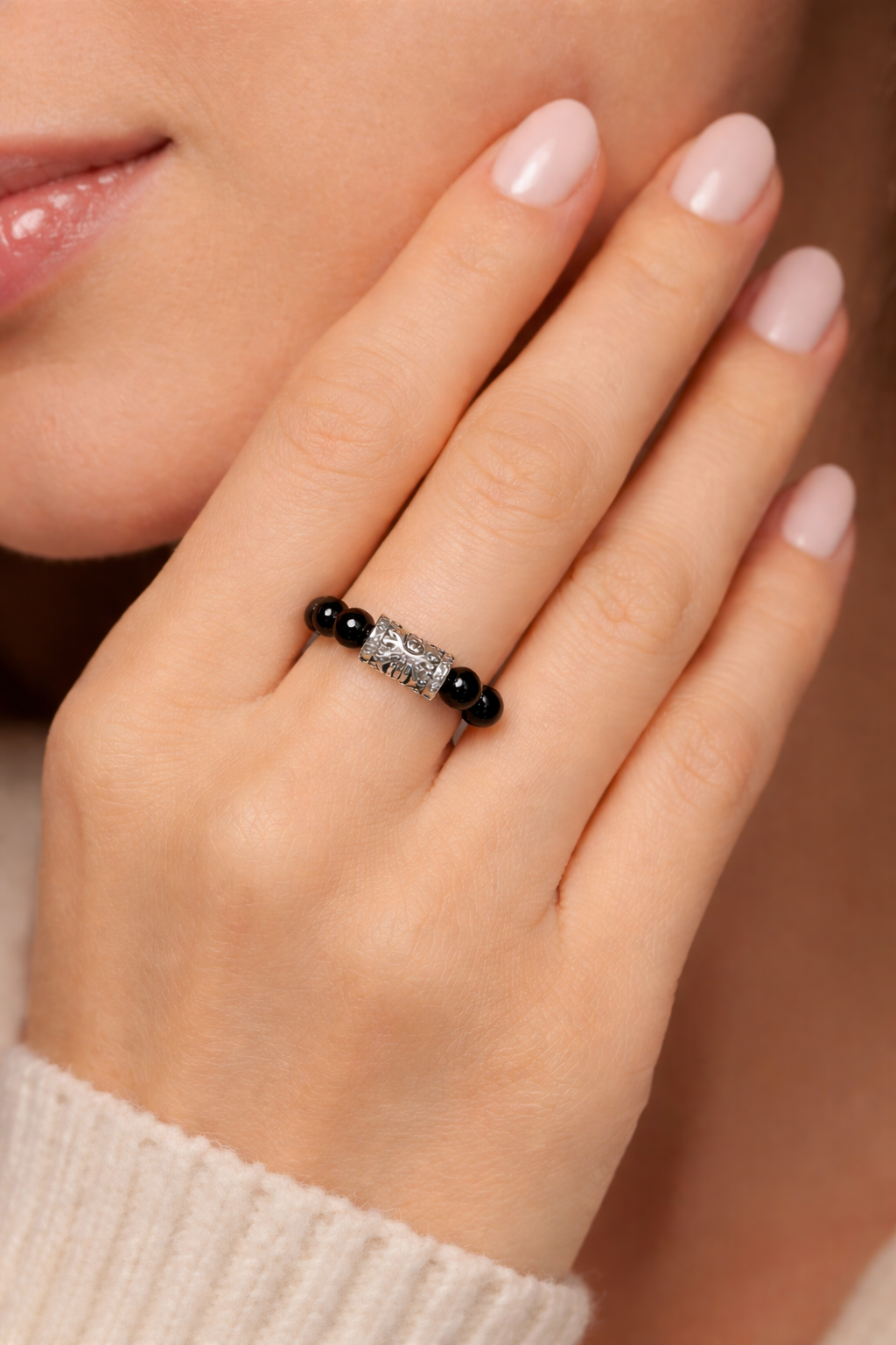 Close-up of a hand wearing a ring with black beads and silver band.